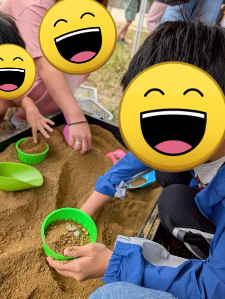 屋外体験イベントで土の中にある鉱石探しをする児童達
