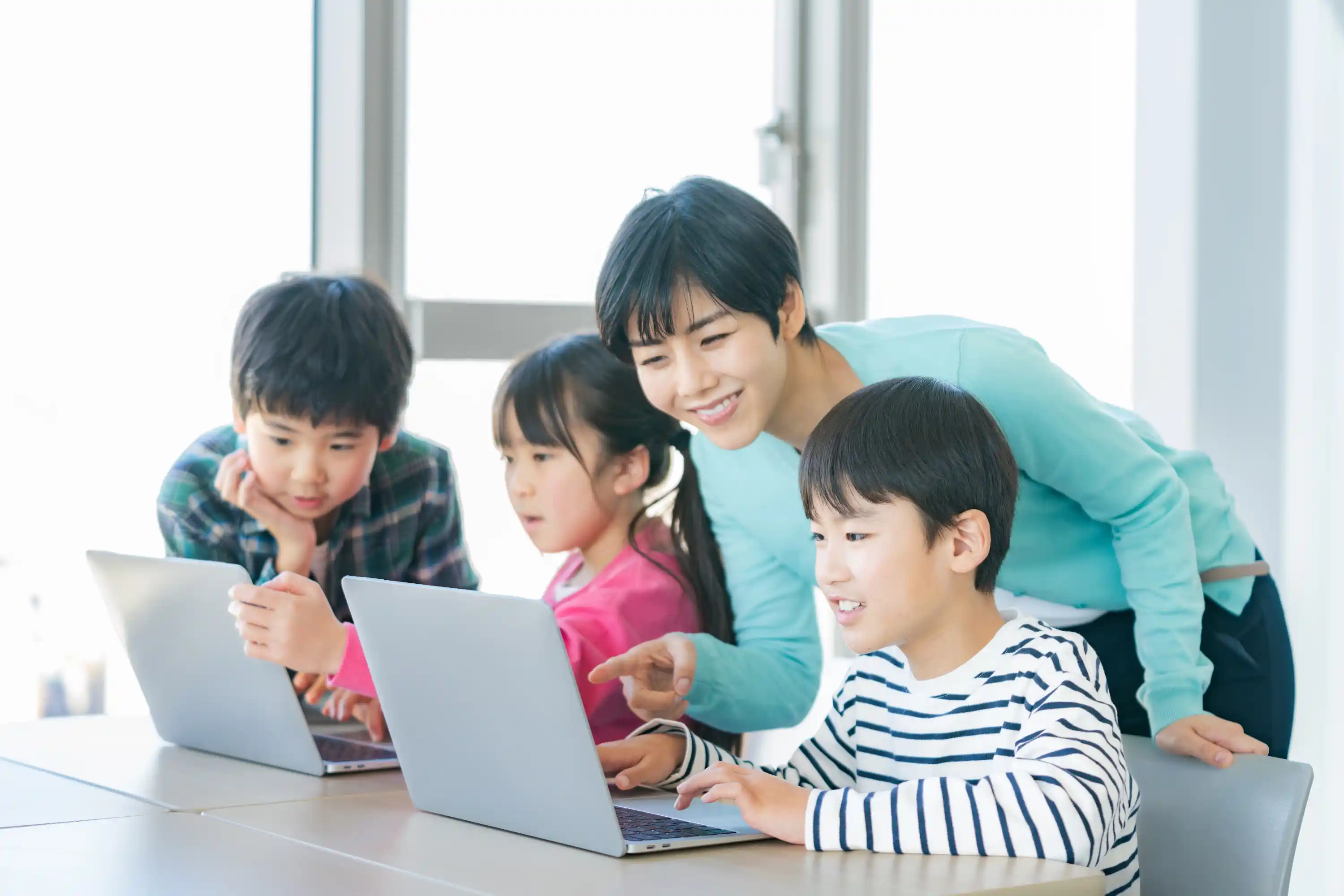 大人が子どもにパソコンでプログラミングを教えている