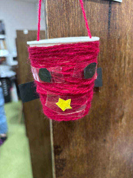 放課後等デイサービスの児童がハロウィンイベント用に作成した、赤い毛糸で装飾された紙コップの工作