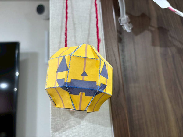 放課後等デイサービスの児童がハロウィンイベント用に作成した、赤い毛糸で装飾されたカボチャのペーパークラフト