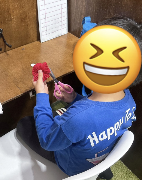 放課後等デイサービスの児童が巻いた毛糸をハサミで加工する様子