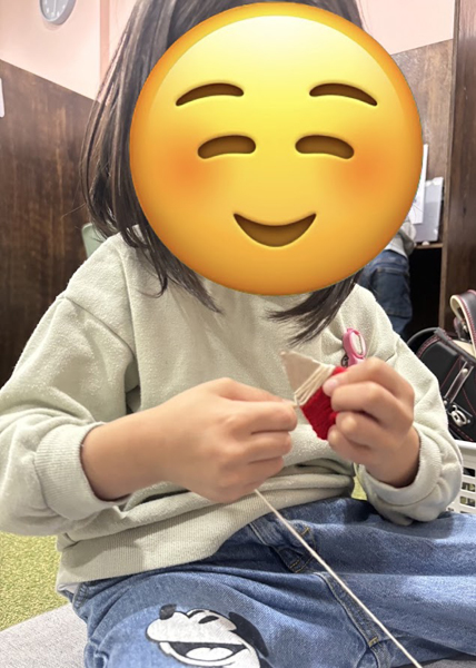 放課後等デイサービスの児童が型紙に毛糸を巻き付け、サンタクロースを作ろうとしています