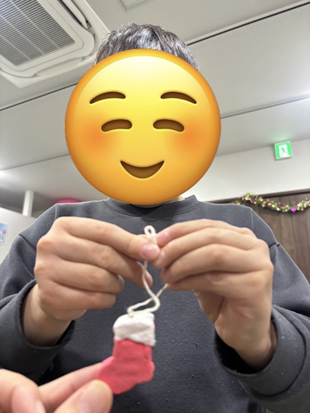 放課後等デイサービスの児童が紙粘土で作った靴に紐を通す様子