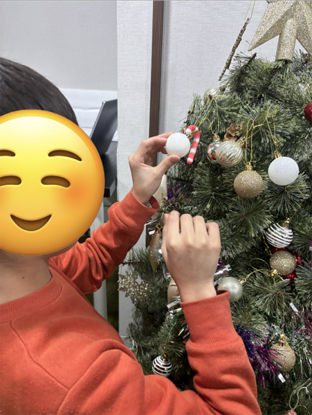 放課後等デイサービスの児童がクリスマスツリーにオーナメントを取り付ける様子