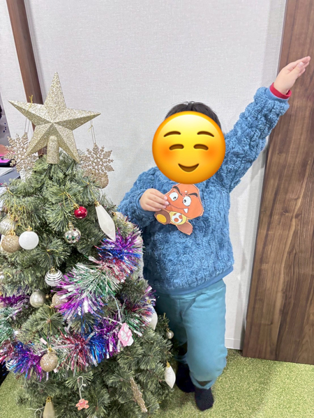 放課後等デイサービスの児童が完成させた福笑いと一緒に写真を撮っています。