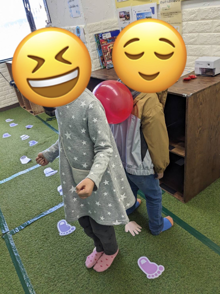 ペアになって背中で風船を挟んだままゴールを目指す配達ゲームの様子