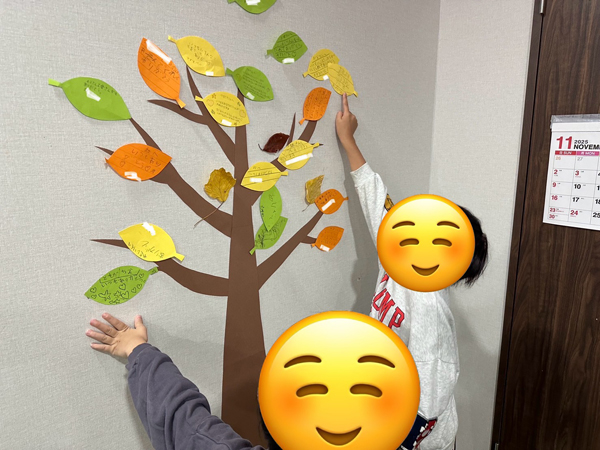 感謝を表すメッセージを集めた「感謝の木」を児童が壁に貼る様子